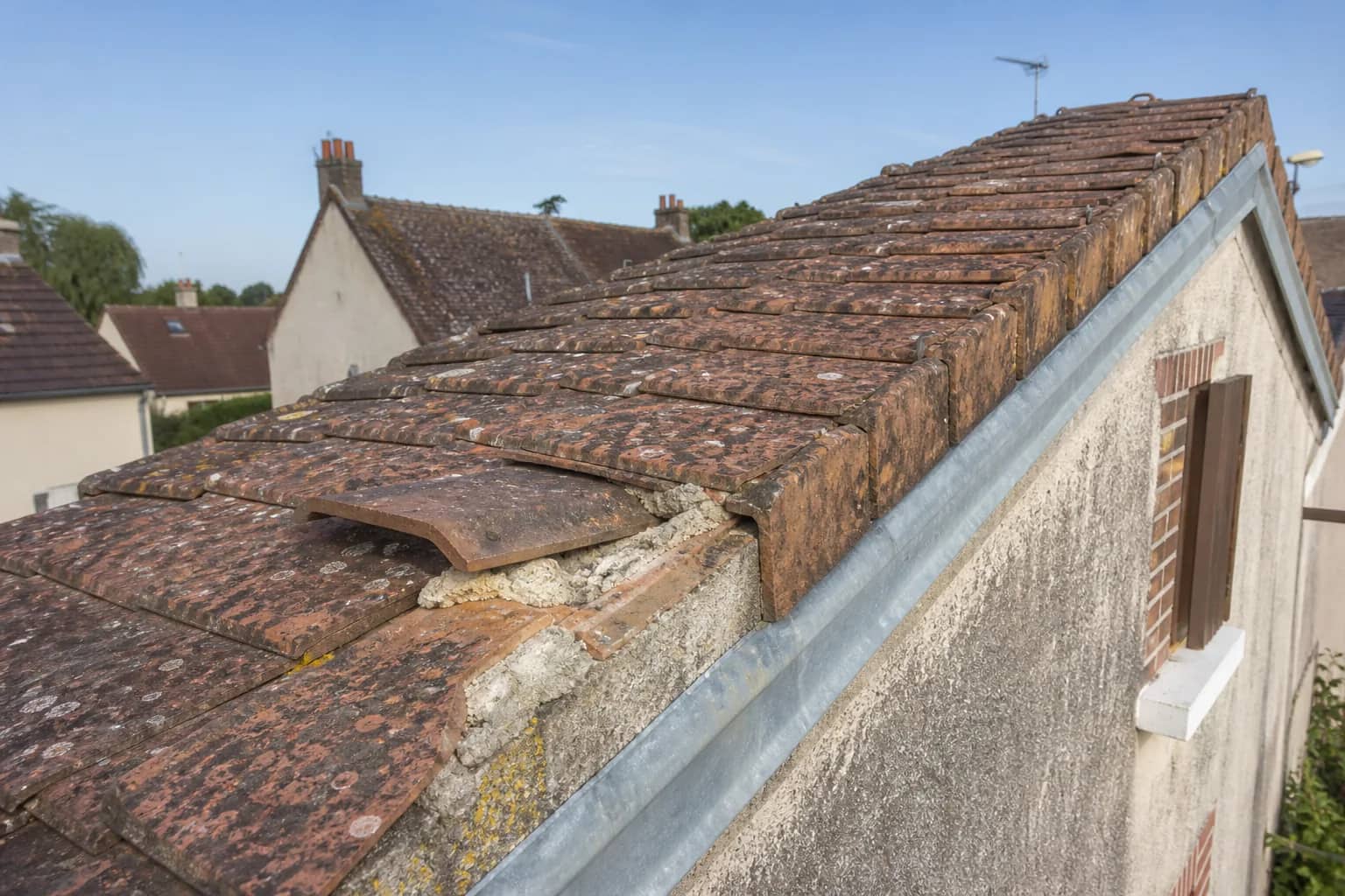 Tuiles faîtières vieillies et élément déplacé sur une maison du Loiret